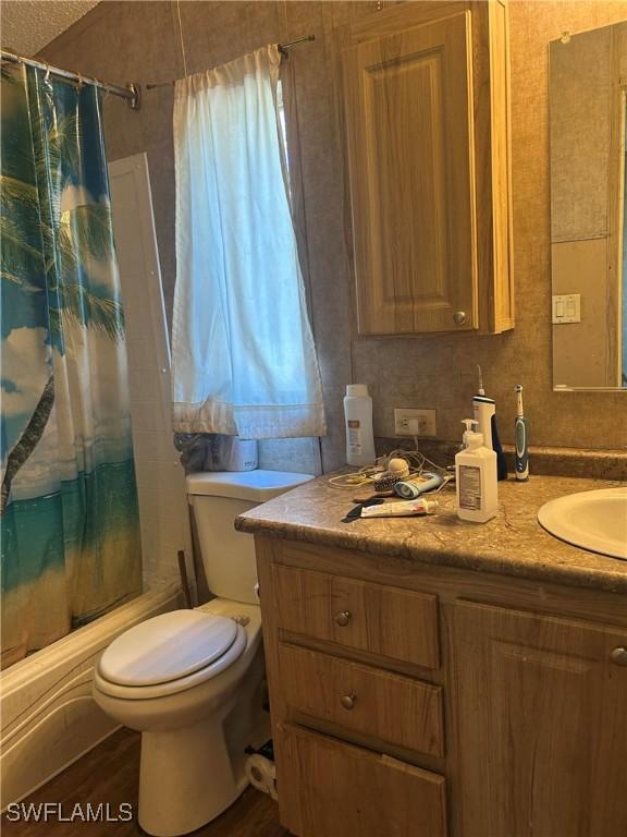 full bathroom featuring vanity, hardwood / wood-style flooring, toilet, and shower / tub combo with curtain