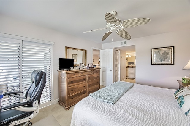 bedroom featuring ceiling fan, light colored carpet, and connected bathroom