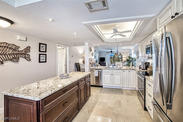 kitchen with white cabinetry, appliances with stainless steel finishes, kitchen peninsula, and a tray ceiling