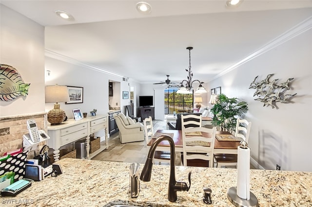 dining space with crown molding, sink, and ceiling fan with notable chandelier