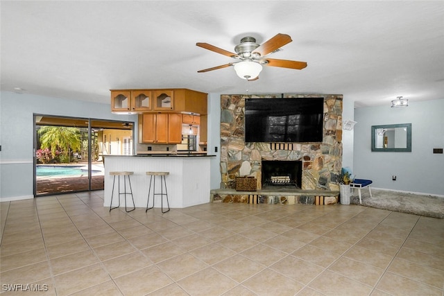 kitchen featuring light tile patterned floors, a fireplace, dark countertops, and brown cabinets