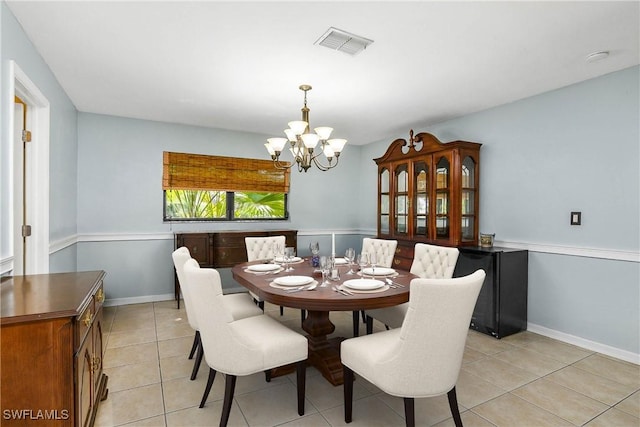 dining room featuring light tile patterned floors, baseboards, visible vents, and a notable chandelier