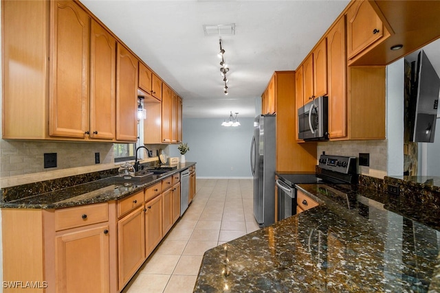 kitchen featuring stainless steel appliances, tasteful backsplash, light tile patterned flooring, a sink, and dark stone counters