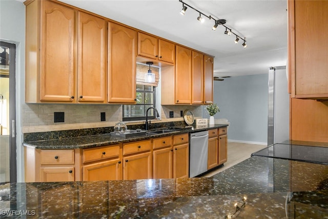 kitchen with a sink, baseboards, appliances with stainless steel finishes, tasteful backsplash, and dark stone countertops