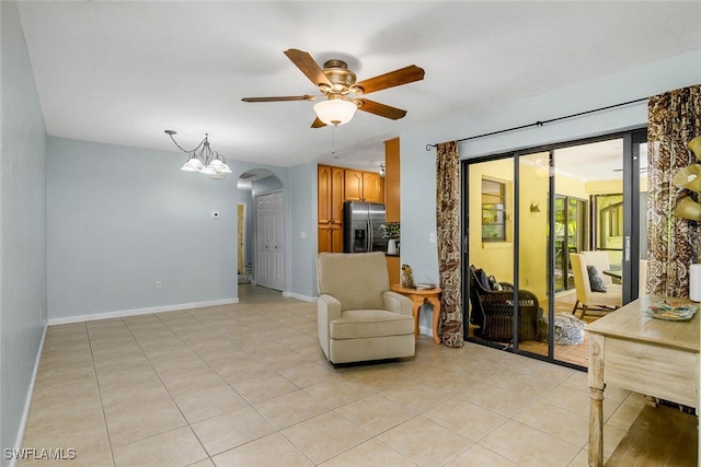 sitting room with arched walkways, ceiling fan, light tile patterned flooring, and baseboards