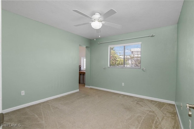 carpeted empty room featuring baseboards and a ceiling fan