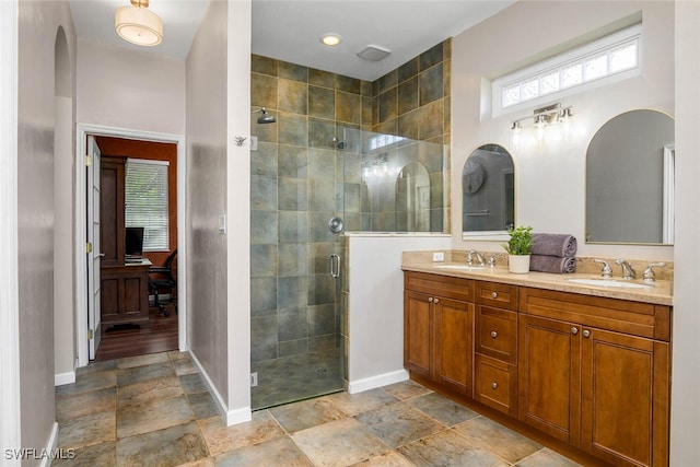 bathroom with a sink, a shower stall, baseboards, and double vanity