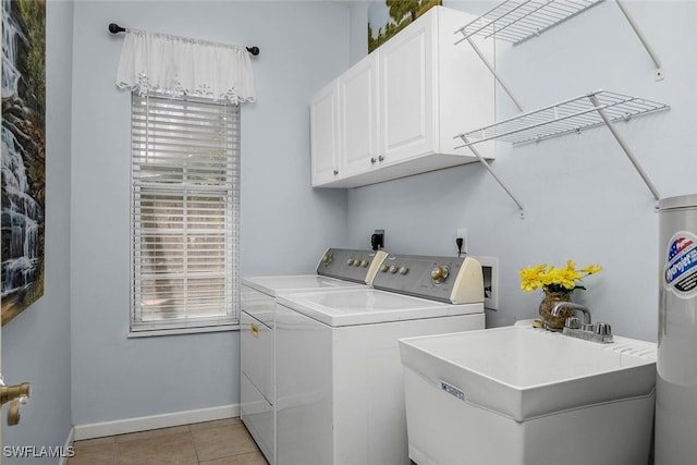 washroom featuring light tile patterned floors, a sink, baseboards, cabinet space, and washing machine and clothes dryer