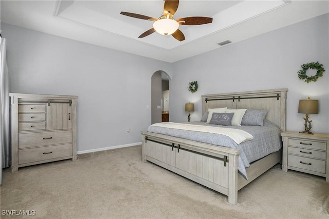 bedroom with arched walkways, a raised ceiling, visible vents, light carpet, and baseboards