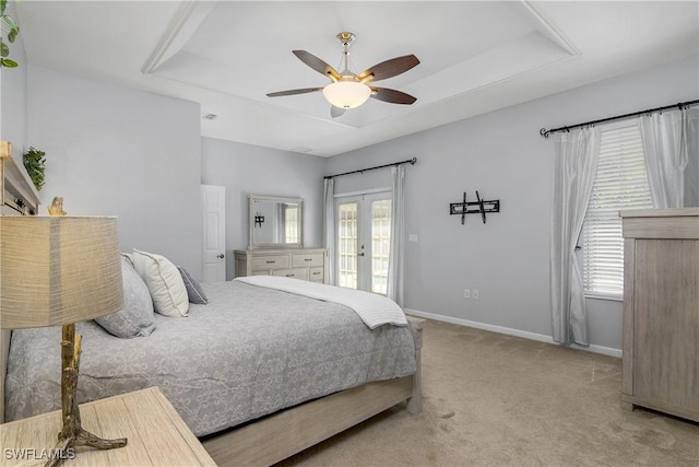 bedroom with carpet floors, baseboards, multiple windows, and a tray ceiling