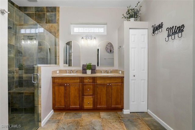 bathroom featuring a sink, a shower stall, baseboards, and double vanity