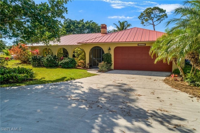 view of front facade featuring metal roof, driveway, an attached garage, and stucco siding