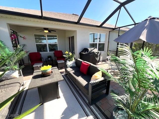 view of patio featuring an outdoor living space, ceiling fan, and glass enclosure