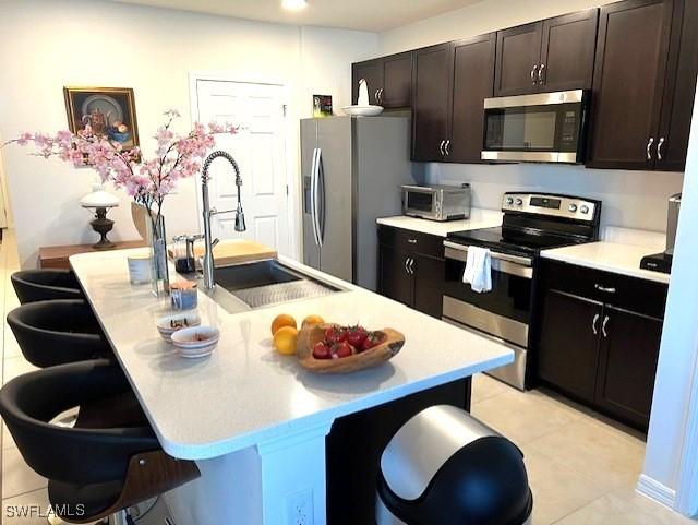 kitchen with appliances with stainless steel finishes, a breakfast bar, a center island with sink, and sink