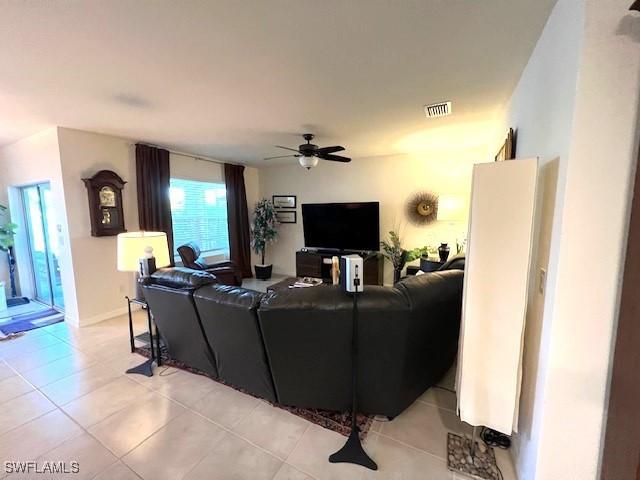living room featuring light tile patterned floors, visible vents, and ceiling fan