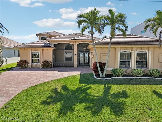 mediterranean / spanish house featuring a front lawn and french doors