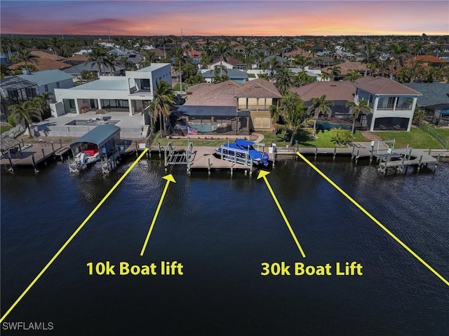 aerial view at dusk with a residential view and a water view