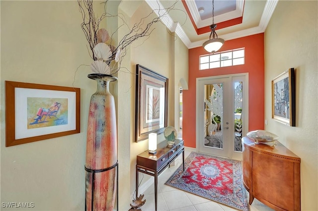 tiled foyer with crown molding and a raised ceiling