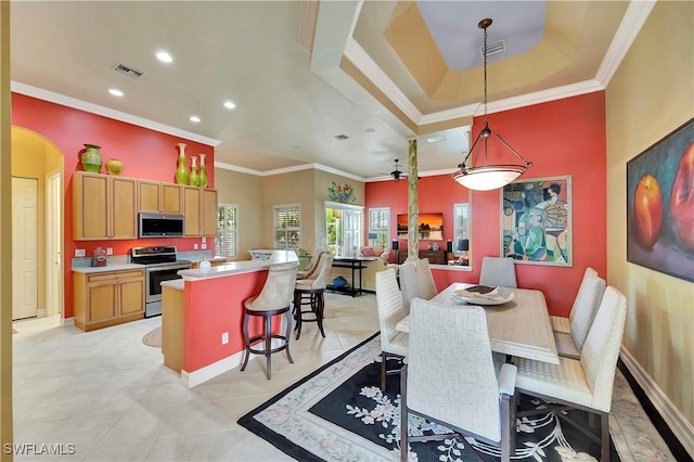 tiled dining area featuring crown molding, a raised ceiling, and ceiling fan