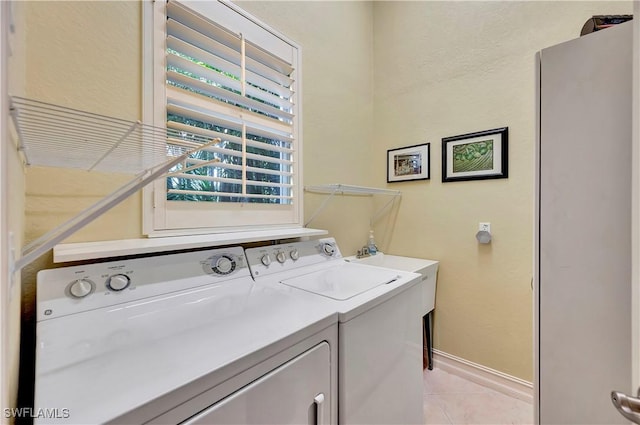 laundry area with washing machine and dryer and light tile patterned floors