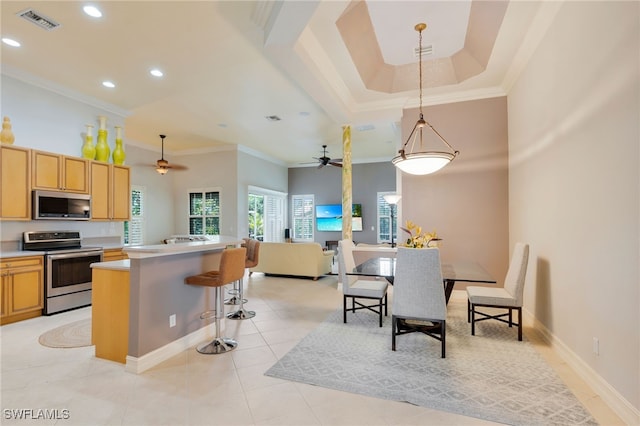 kitchen featuring appliances with stainless steel finishes, a ceiling fan, ornamental molding, recessed lighting, and a center island