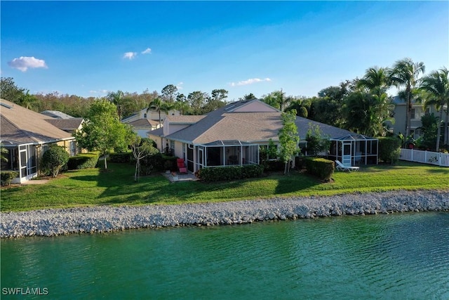 back of property with a water view, a yard, and a lanai