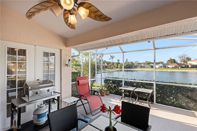 sunroom / solarium with a water view, lofted ceiling, and ceiling fan