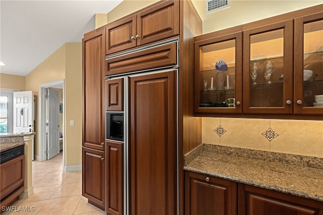 kitchen with lofted ceiling, light tile patterned floors, backsplash, paneled built in fridge, and light stone countertops