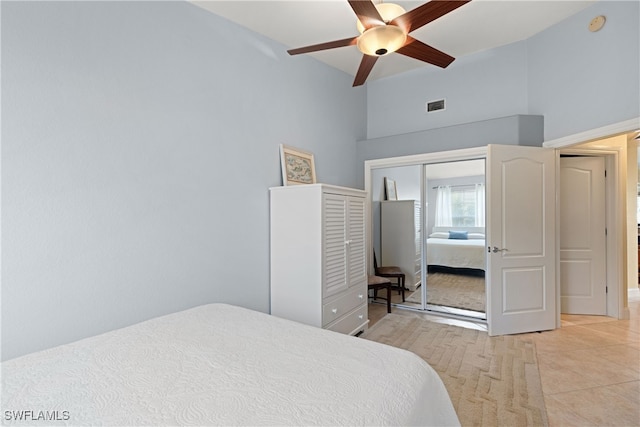 bedroom featuring high vaulted ceiling, light tile patterned floors, ceiling fan, and a closet