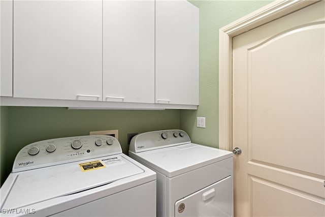 clothes washing area with cabinets and washer and clothes dryer