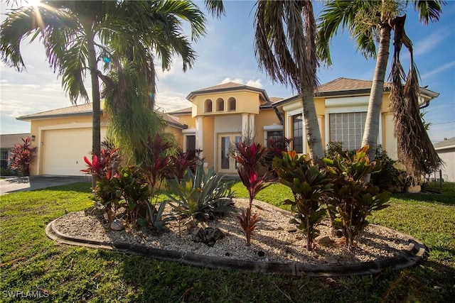 mediterranean / spanish-style home with an attached garage, driveway, a front yard, and stucco siding