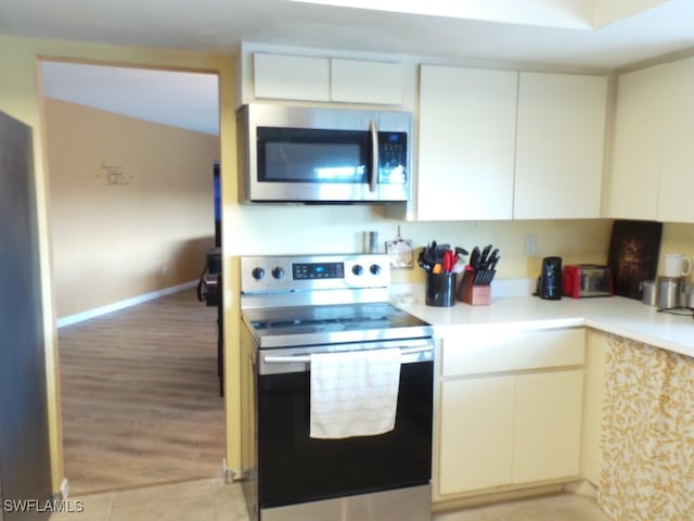 kitchen featuring stainless steel appliances, white cabinets, and light hardwood / wood-style flooring