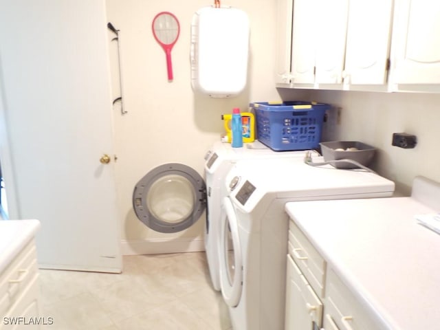 washroom featuring washer and dryer, cabinets, and light tile patterned flooring