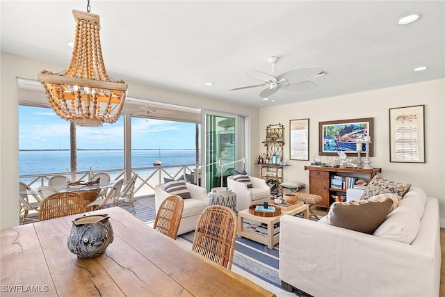 dining space featuring recessed lighting, ceiling fan with notable chandelier, and a water view