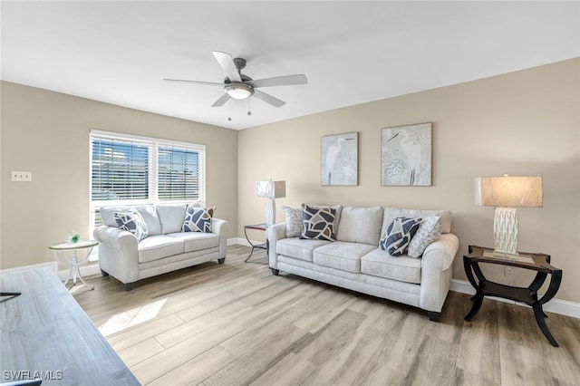 living area with light wood-style floors, baseboards, and a ceiling fan