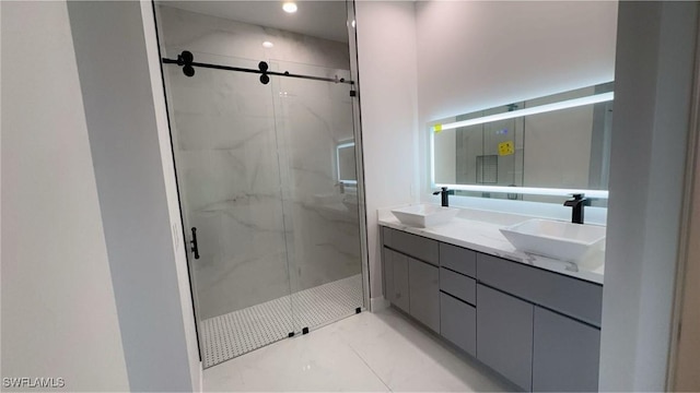 full bath featuring a sink, a marble finish shower, and double vanity