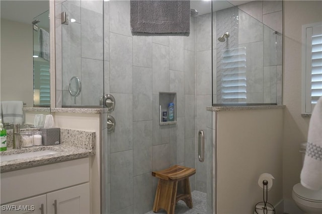 bathroom with a shower with door, vanity, and toilet