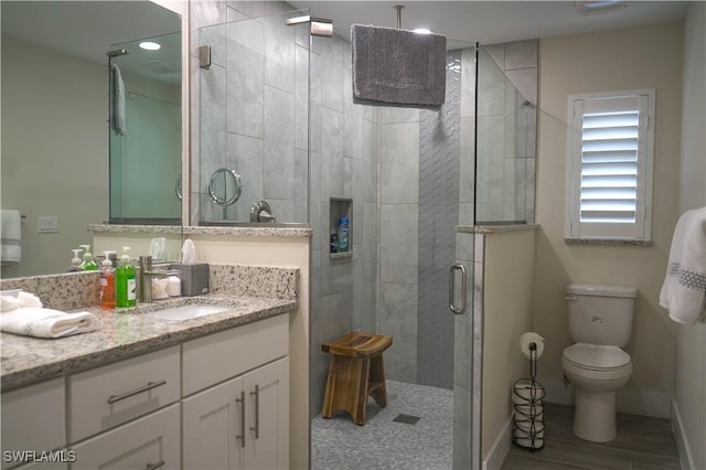 bathroom featuring walk in shower, vanity, toilet, and wood-type flooring