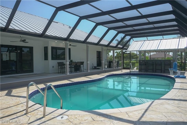 view of swimming pool with a bar, a patio area, ceiling fan, and glass enclosure