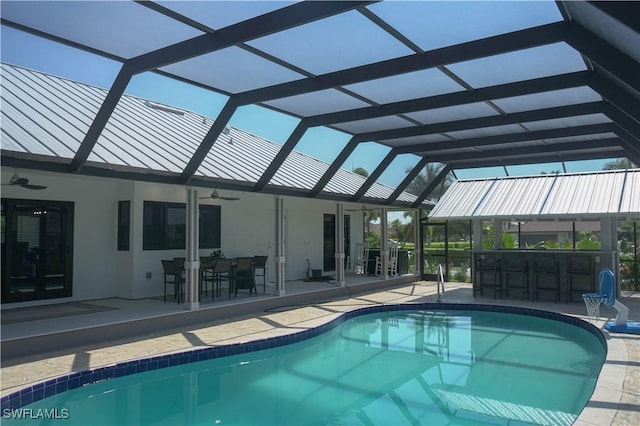 view of pool with a bar, a patio, ceiling fan, and glass enclosure