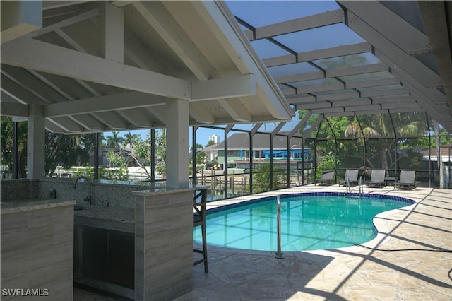 view of swimming pool with a bar, a lanai, and a patio area