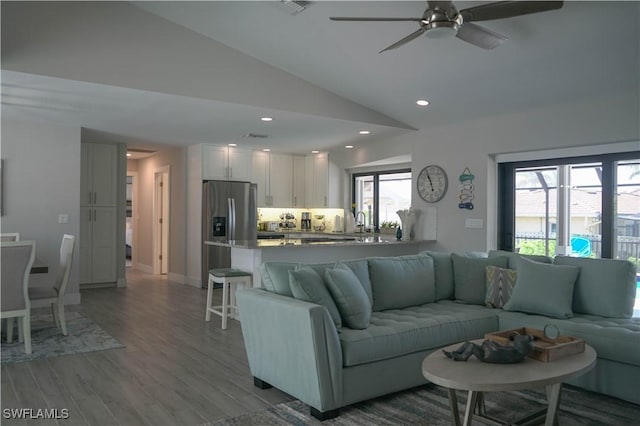 living room featuring sink, vaulted ceiling, light hardwood / wood-style floors, and ceiling fan