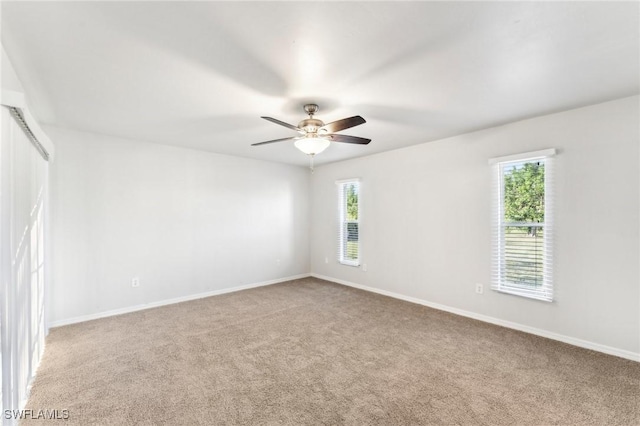 carpeted empty room featuring a healthy amount of sunlight, baseboards, and a ceiling fan