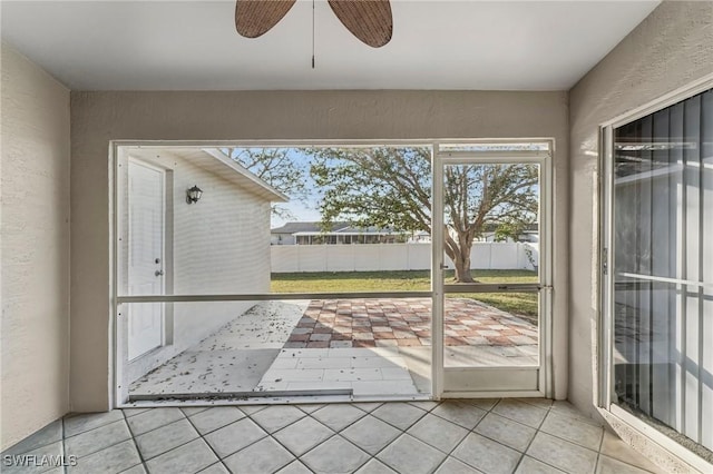 doorway featuring tile patterned floors, a ceiling fan, and a textured wall