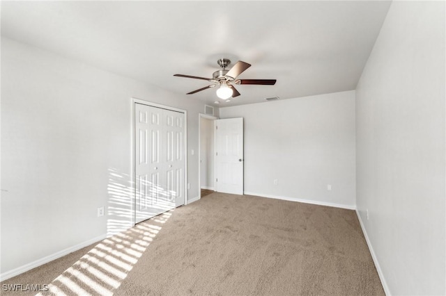 unfurnished bedroom with carpet, a closet, visible vents, a ceiling fan, and baseboards