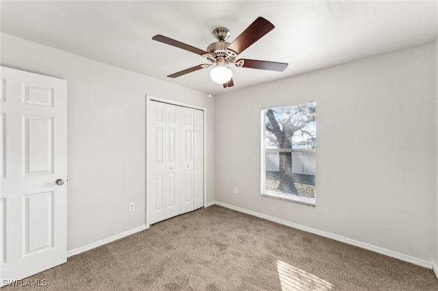 unfurnished bedroom featuring a ceiling fan, baseboards, a closet, and light colored carpet