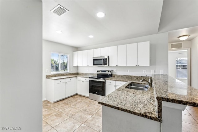 kitchen featuring stone counters, a peninsula, a sink, visible vents, and appliances with stainless steel finishes