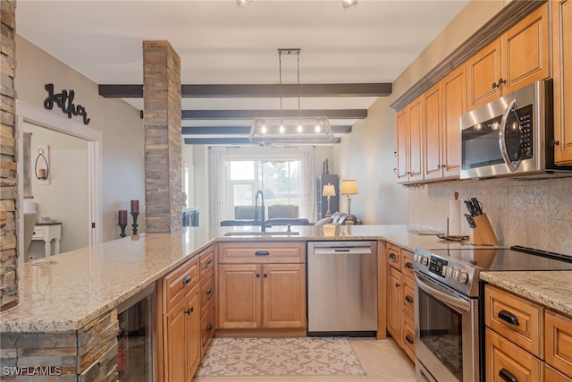 kitchen with hanging light fixtures, appliances with stainless steel finishes, sink, and kitchen peninsula