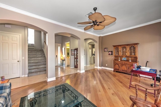 living room with crown molding, ceiling fan, and light wood-type flooring