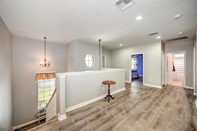 hall featuring a chandelier and light hardwood / wood-style floors